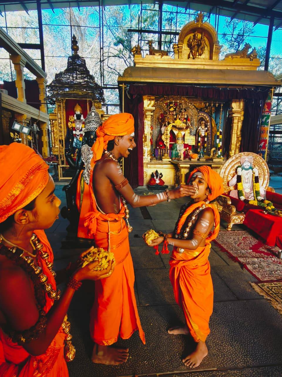 Bālasanyāsis sharing prasāda before the shrine